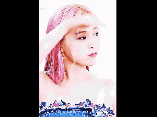 a woman with pink hair is wearing a blue top and denim skirt .