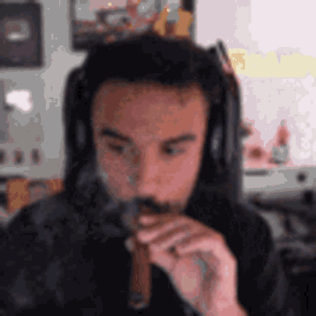 a man wearing headphones is smoking a cigarette while looking at the camera .