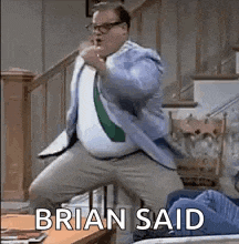 a man in a suit and tie is dancing in a living room with the words `` brian said '' above him .