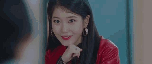 a close up of a woman wearing a red leather jacket and hoop earrings .