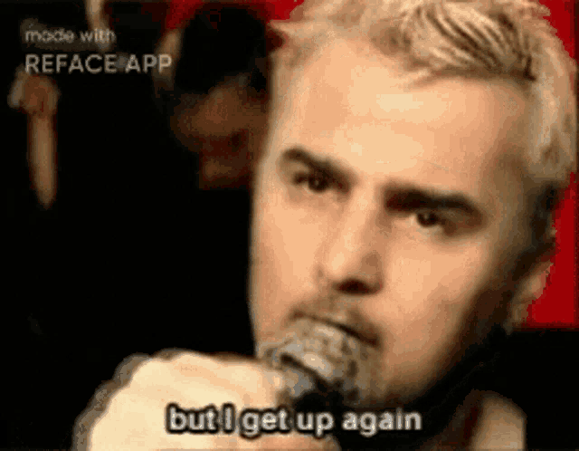 a man singing into a microphone with the words but i get up again
