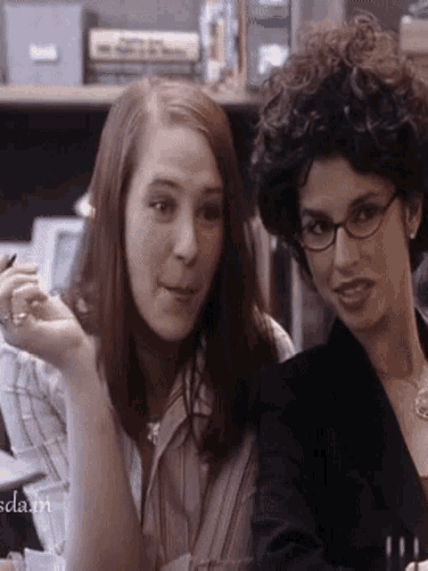two women are sitting next to each other and the words scla.m are on the bottom of the image