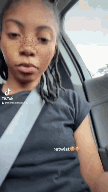 a woman with freckles is wearing a black shirt and a seat belt .