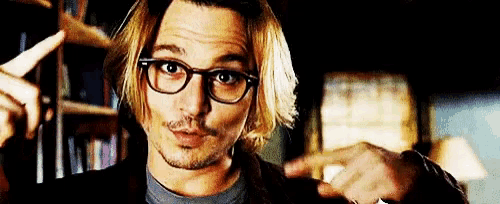 a man wearing glasses is pointing his finger at something