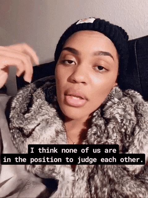 a woman wearing a fur coat and a beanie says i think none of us