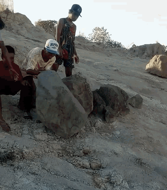 a man wearing a hat that says denver is looking at a large rock