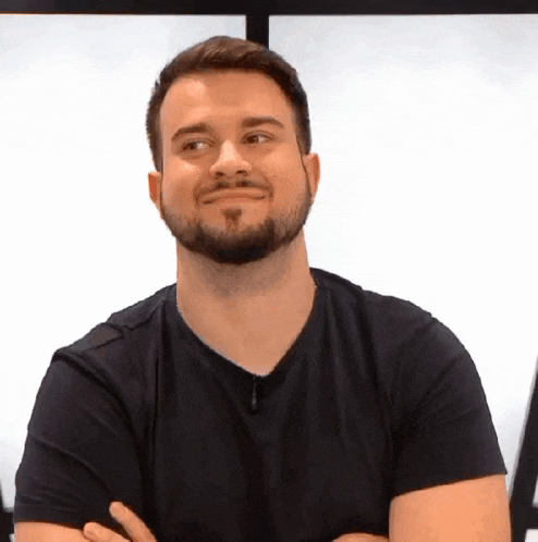 a man with a beard is standing with his arms crossed