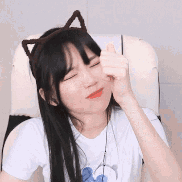 a girl with cat ears on her head is giving a thumbs up