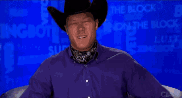 a man wearing a cowboy hat and a purple shirt is making a face