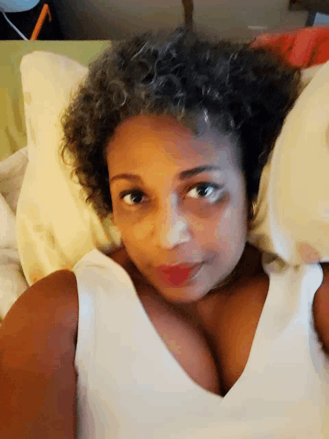a woman laying on a bed with a white shirt on