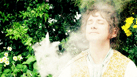 a man is smoking a hookah in a garden with his eyes closed