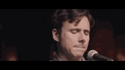 a close up of a man singing into a microphone .