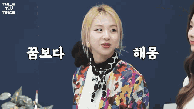 a woman in a colorful jacket is standing next to another woman with chinese writing on the bottom