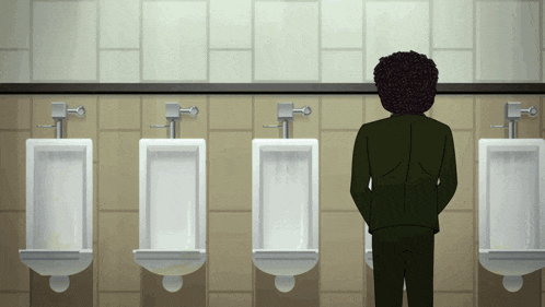 a man in a suit stands in front of urinals in a public bathroom