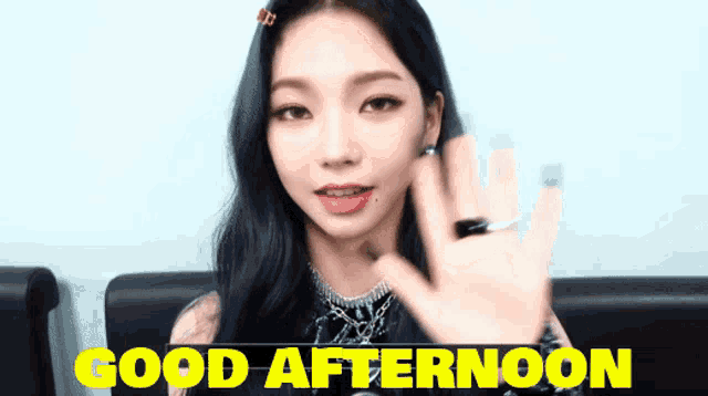 a woman waves her hand in front of a sign that says " good afternoon "