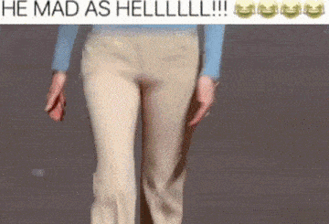 a woman in khaki pants and a blue shirt is walking down a street .