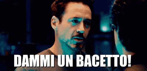 a man with a beard is standing next to another man and says dammi un bacetto .