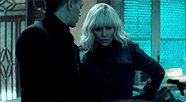 a man and a woman are standing next to each other in a dark room looking at each other .