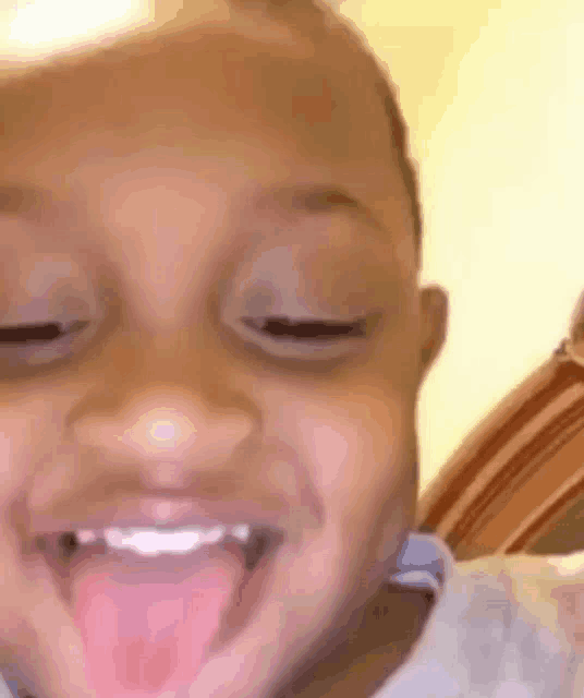 a close up of a child making a funny face with his tongue hanging out .
