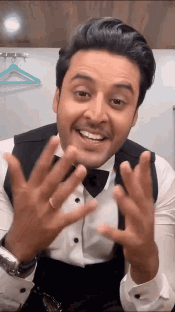 a man wearing a tuxedo and bow tie is making a funny face .