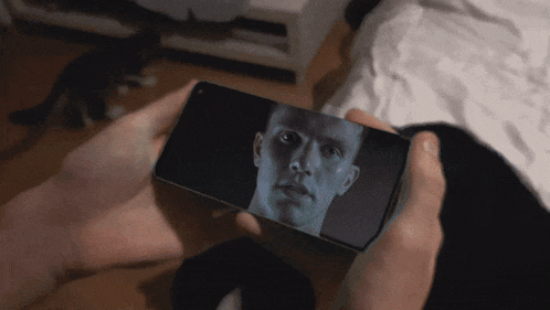 a person holding a cell phone with a man 's face on the screen