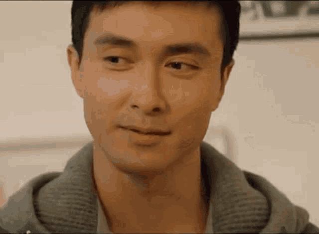 a close up of a man 's face with a gray jacket on