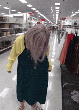 a woman in a plaid dress is standing in a store with clothes hanging on racks