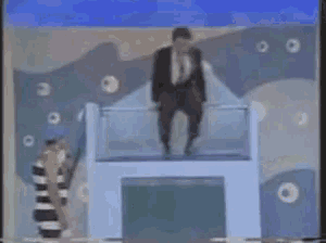 a man in a suit and tie is sitting on a podium in front of a woman in a striped dress .