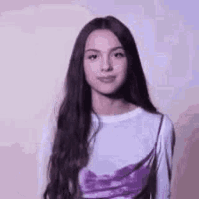 a young woman with long dark hair is wearing a white shirt and a purple top .