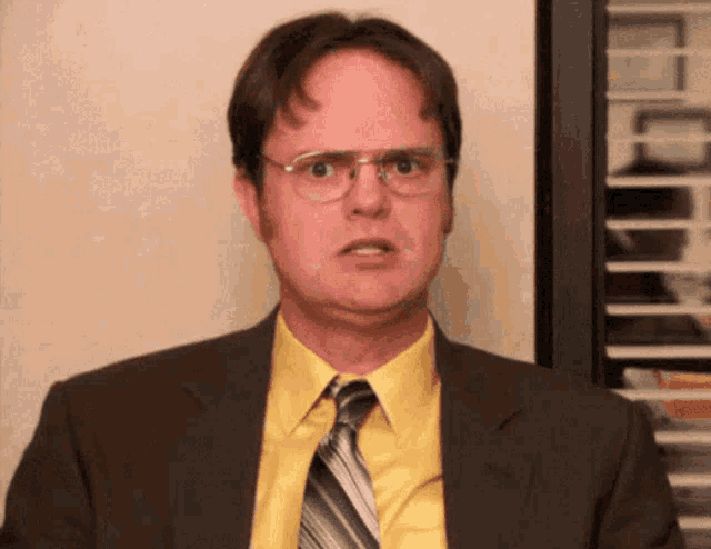 a man wearing glasses and a suit looks surprised