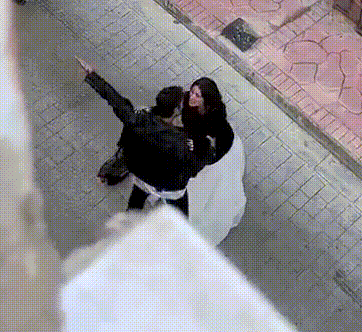 a man and a woman are standing on a sidewalk and the man is pointing at something