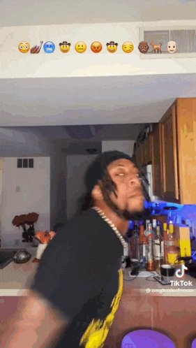 a man in a kitchen with emojis on the wall