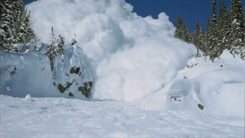 a large pile of snow is coming down a snowy hillside