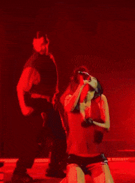 a woman in a red corset and american flag shorts is being held by a man