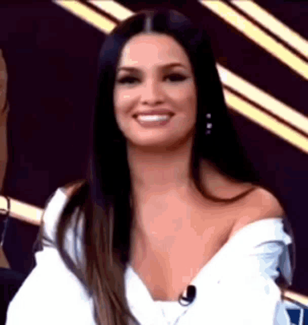a woman with long black hair is smiling and wearing a white shirt .