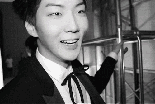 a black and white photo of a young man wearing a suit and tie .