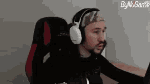 a man wearing headphones and a headband is sitting in a gaming chair .