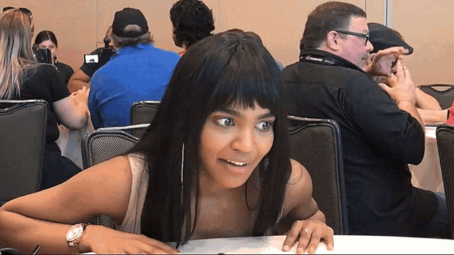 a woman is sitting at a table with a man wearing a lanyard that says canon