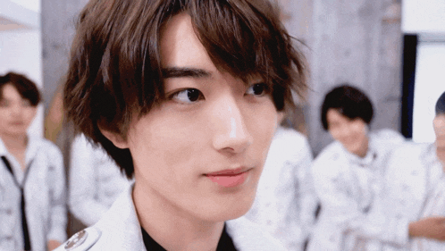 a close up of a young man 's face in front of a group of men