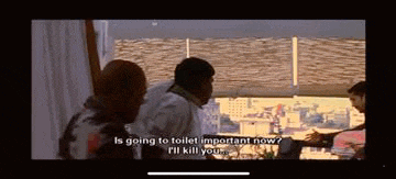 a group of people are standing in front of a window and one of them is talking to another man .