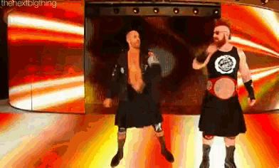 two wrestlers in kilts are standing on a stage .