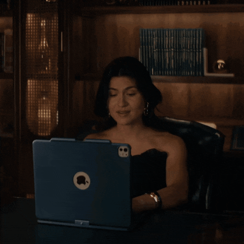 a woman is sitting at a desk using an apple laptop