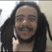 a man with dreadlocks and braces is smiling .