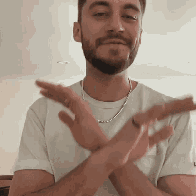 a man with a beard and a white shirt is clapping his hands