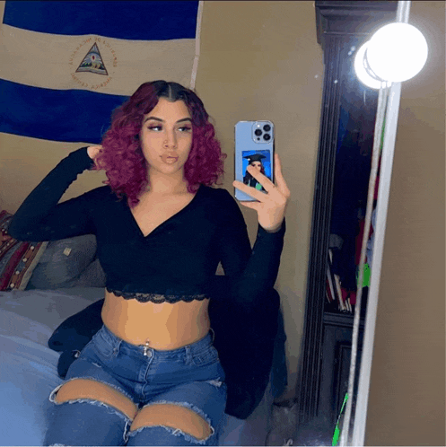 a woman taking a picture of herself in front of a nicaraguan flag
