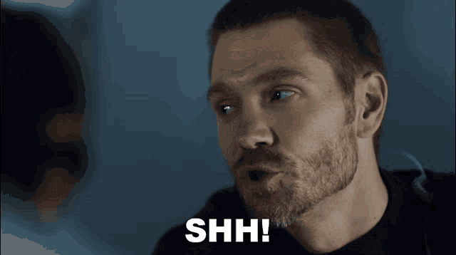 a man with a beard is saying shh with his mouth wide open