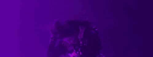 a woman in a purple dress is dancing in front of a purple background .