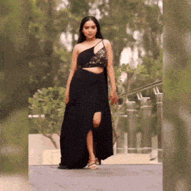 a woman is wearing a black dress with a high slit and a crop top