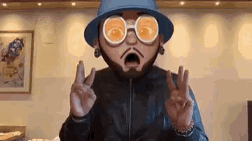 a man wearing a hat and sunglasses is giving a peace sign .