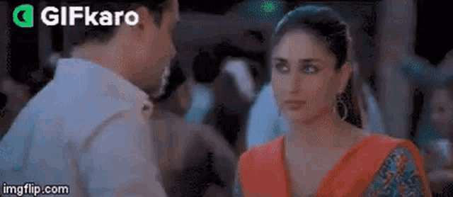 a man and a woman are looking at each other in a crowded room in a movie .